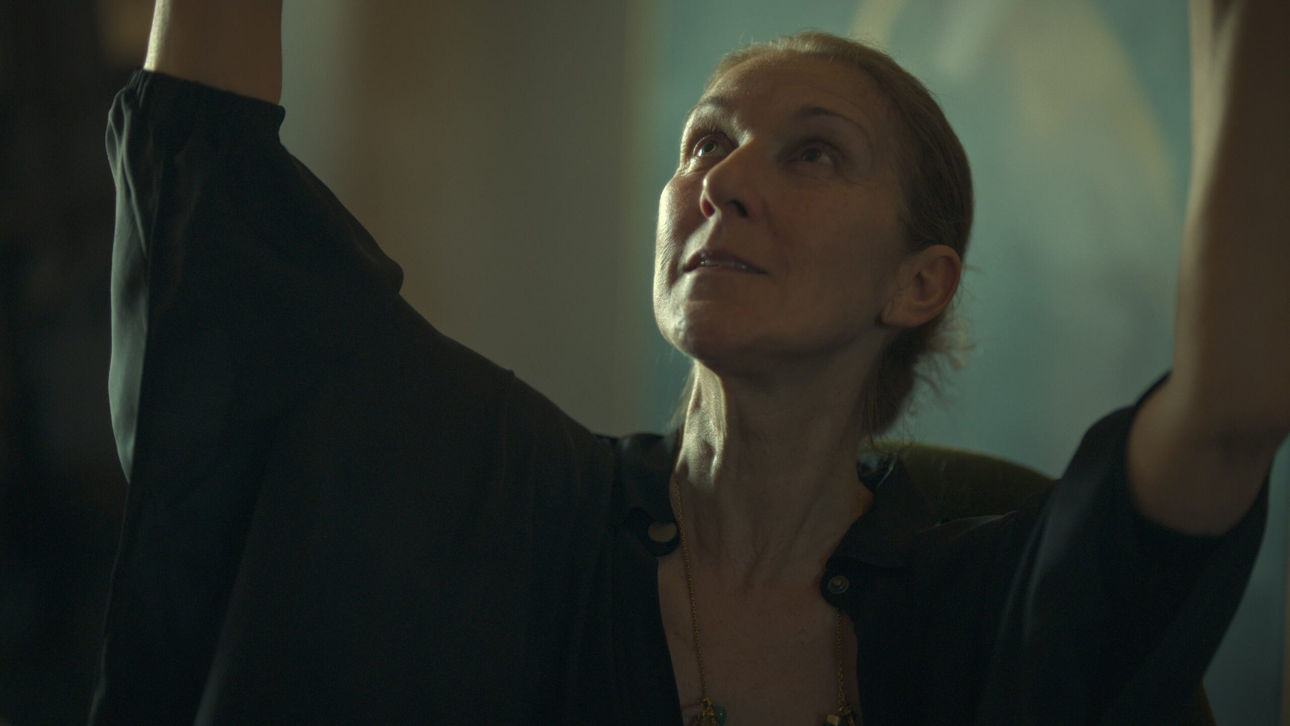 Celine Dion, without makeup, with her arms open and raised